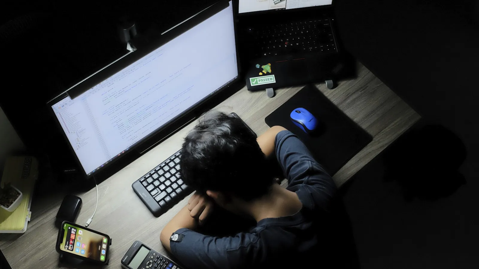暗い部屋でモニターに向かっている人の後ろ姿